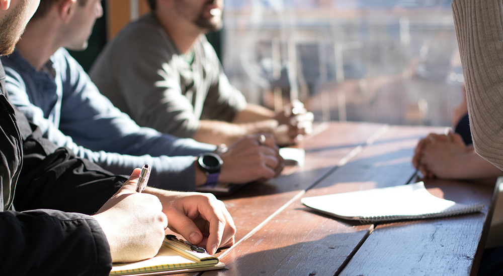 Colleagues gathered around a wooden table strategising